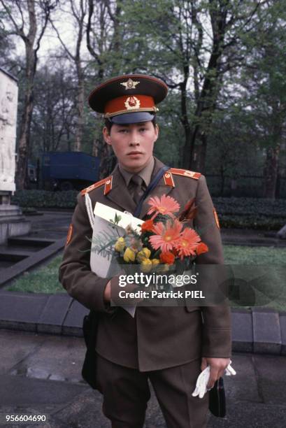 Soldat russe tenant un bouquet de fleurs lors du 40e anniversaire de la fin de la Seconde Guerre mondiale le 8 mai 1985 à Berlin en RDA.