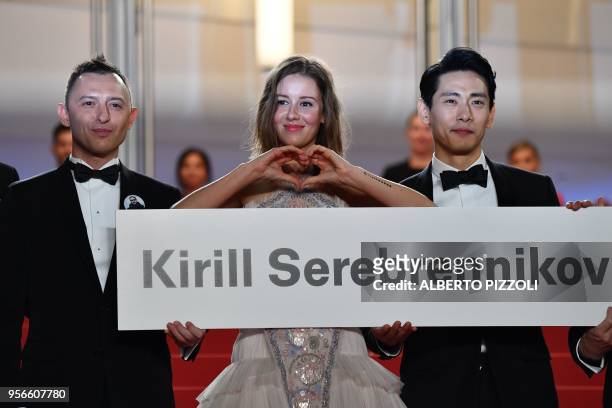 Russian actor Roma Zver, Russian actress Irina Starshenbaum and German actor Teo Yoo hold a cardboard bearing the name of Russian director Kirill...