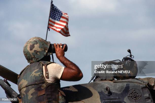 Un Marine américain regarde avec des jumelles près d'un véhicule militaire en septembre 1983 au Liban.