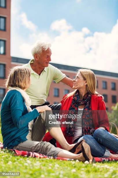elderly parents with daughter having picnic in town - town meeting stock pictures, royalty-free photos & images