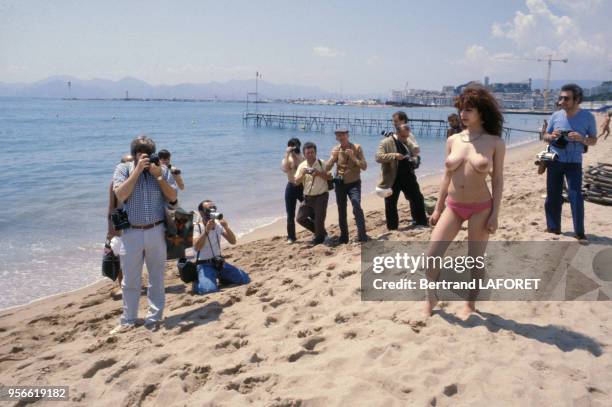 Starlette en maillot de bain topless photographiée par la presse sur la plage en mai 1980 à Cannes, France.