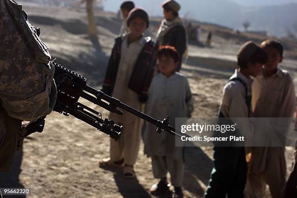 Village children look out at a US Army soldier from a Provincial Reconstruction Team on January 9, 2010 in Pushtay, Afghanistan. The soldiers, from...