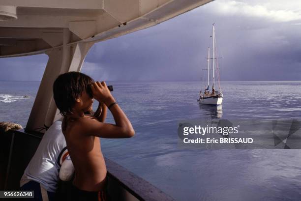 Jeune garçon regardant la mer avec des jumelles en 1984 en Polynésie française.