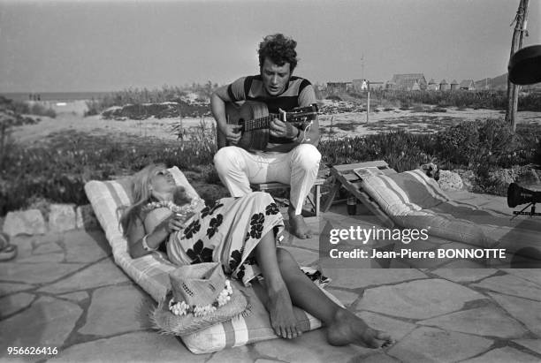 Brigitte Bardot et Johnny Hallyday jouant de la guitare sur une plage en août 1967 à Saint-Tropez, France.