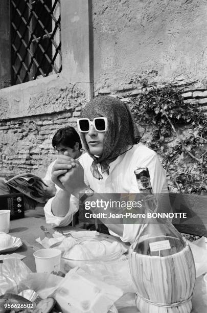 Alain Delon grimé en femme à l'aide d'un foulard et d'épaisses lunettes noires en mars 1967 à Rome, Italie.