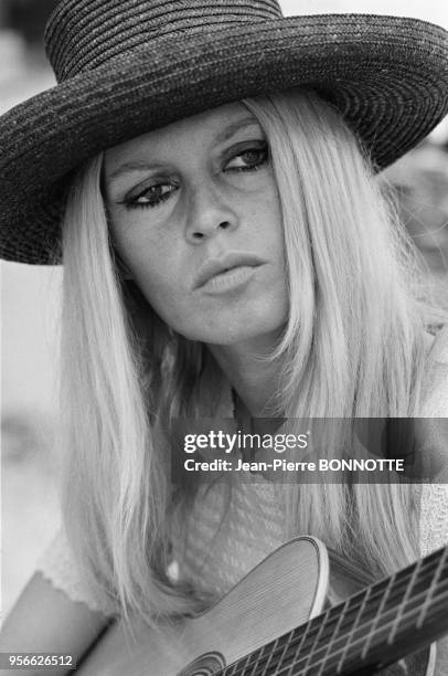Brigitte Bardot jouant de la guitare sur une plage en août 1967 à Saint-Tropez, France.