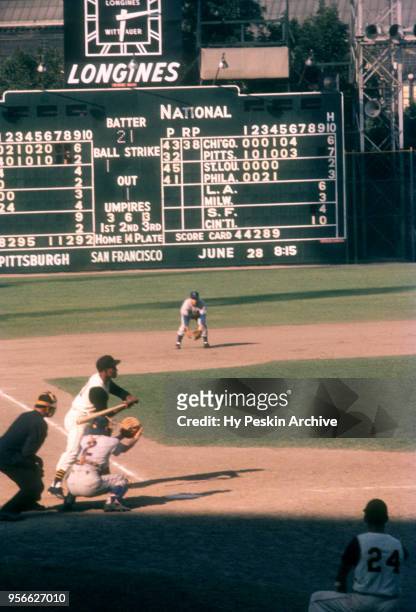 Roberto Clemente of the Pittsburgh Pirates bats as third baseman Ron Santo and catcher El Tappe of the Chicago Cubs defend as umpire Ed Sudol sets up...