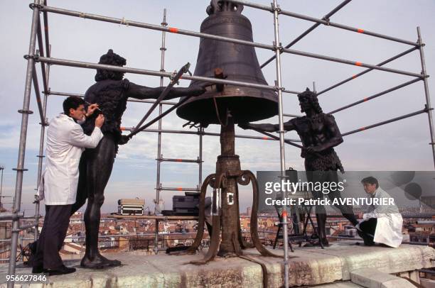 Techniciens travaillant sur les deux Maures battant les heures avec leur marteau au sommet de la célèbre Tour de l'Horloge de la place Saint-Marc en...