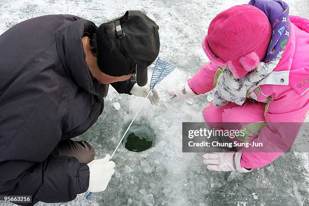 South Korean anglers cast lines through holes into a frozen river during a contest to catch Mountain Trout on January 9, 2010 in Hwacheon-gun, South...