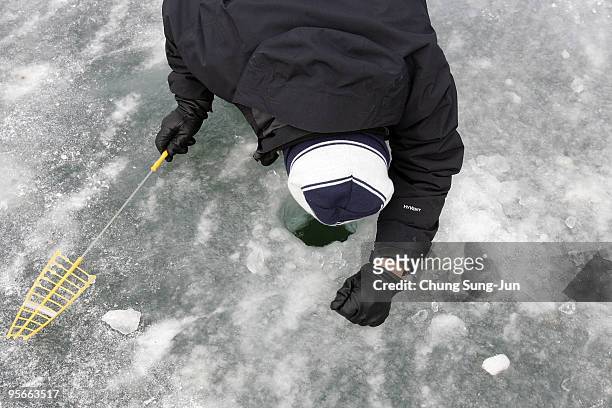 South Korean angler cast line through hole into a frozen river during a contest to catch Mountain Trout on January 9, 2010 in Hwacheon-gun, South...