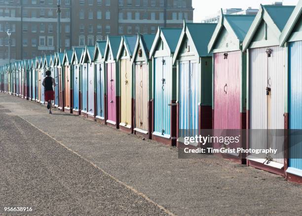 a jogger passing by a row of multi-coloured beach huts - light blue tiled floor stock pictures, royalty-free photos & images