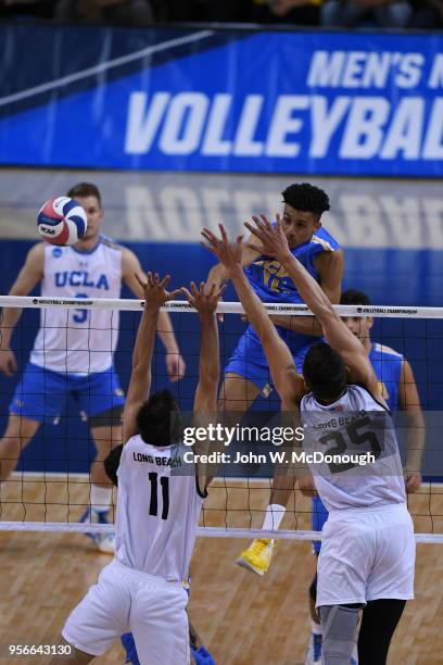 Daenan Gyimah of the UCLA Bruins spikes past TJ DeFalco and Nick Amado of the Long Beach State 49ers during the Division 1 Men's Volleyball...