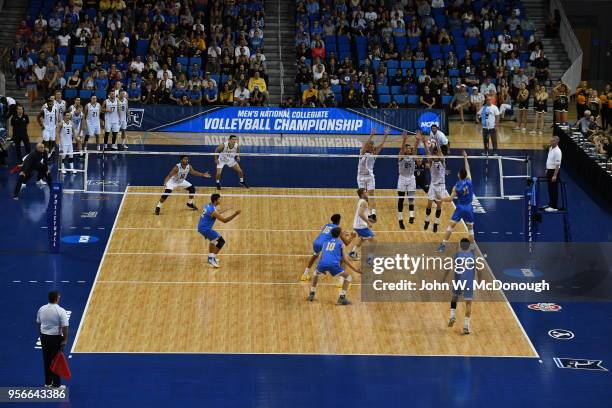 Christian Hessenauer of the UCLA Bruins spikes the ball towards Kyle Ensing, Nick Amado and Bjarne Huus of the Long Beach State 49ers during the...