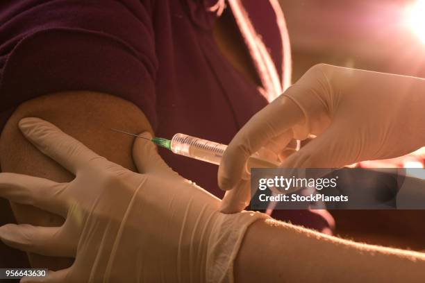close up unrecognizable nurse giving injection to senior women - surgical needle stock pictures, royalty-free photos & images