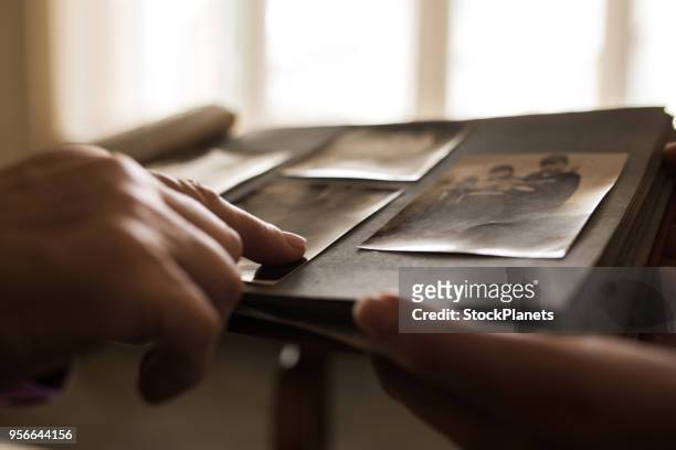 mano humana apuntando a la foto en el álbum de fotos de cerca - fotografía producto de arte y artesanía fotografías e imágenes de stock