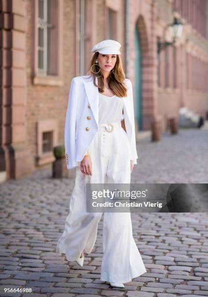 Alexandra Lapp wearing a white cotton blazer with gold buttons by Balmain, linen Palazzo pants with a high waist belt in white by Zimmermann, a white...