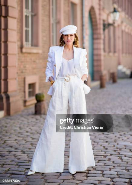 Alexandra Lapp wearing a white cotton blazer with gold buttons by Balmain, linen Palazzo pants with a high waist belt in white by Zimmermann, a white...