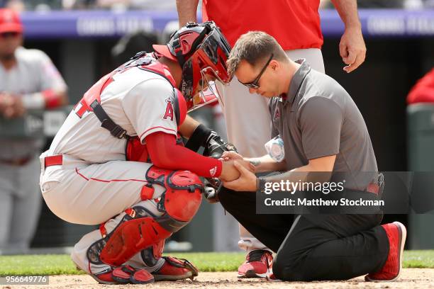 Catcher Rene Rivera of the Los Angeles Angels of Anaheim is attended to by trainer Adam Nevala in the fourth inning against the Colorado Rockies at...