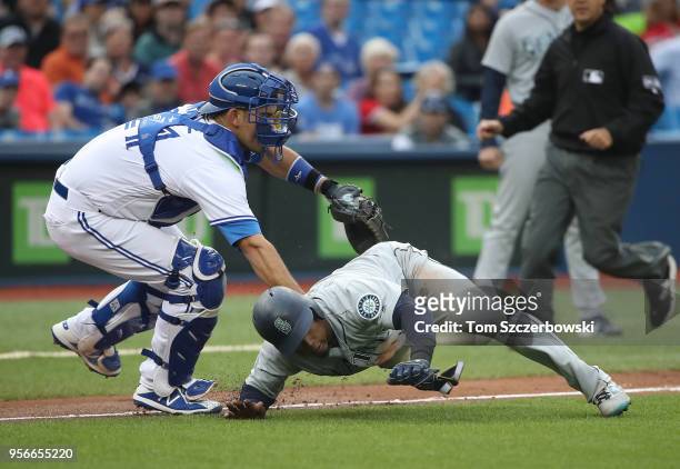 Jean Segura of the Seattle Mariners is tagged out by Luke Maile of the Toronto Blue Jays as he is caught in a run-down during MLB game action at...
