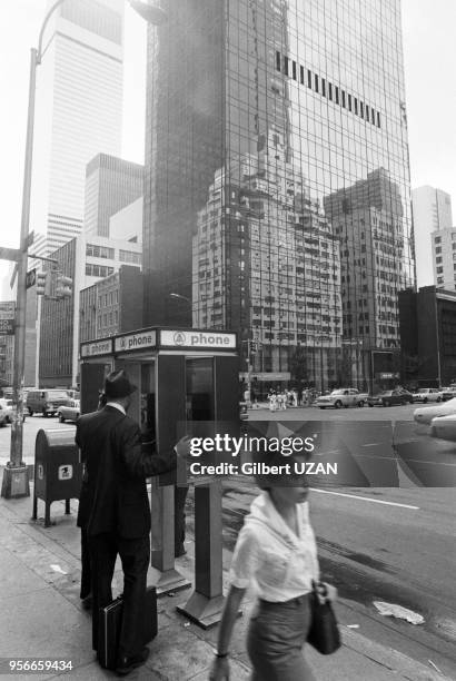 Un homme téléphone dans une cabine téléphonique le long d'une avenue à New York en aout 1977, Etats-Unis.