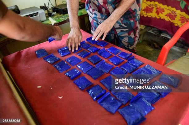 This photograph taken on April 6, 2018 shows a Bangladesh Border Guard laying out small bags of the drug "yaba" recovered from a passenger bus in a...