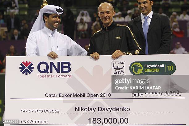 Russia's Nikolay Davydenko receives the winner's cheque from Sheikh Nasser al-Khulaifi, the president of Qatar's Tennis Federation, after beating...