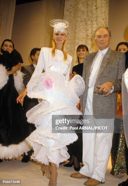 Pierre Cardin et une mannequin en robe de mariée lors du défilé Cardin hiver 1989 en juillet 1989 à Paris, France.