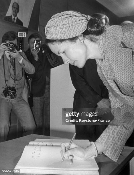 Madame Giscard d'Estaing signant un livre d'or.