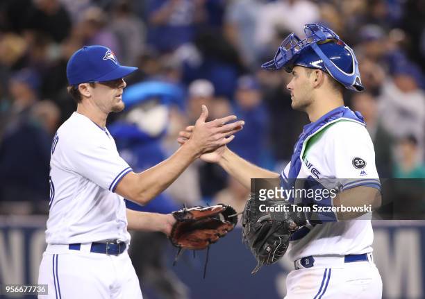 Tyler Clippard of the Toronto Blue Jays celebrates a victory with Luke Maile during MLB game action against the Seattle Mariners at Rogers Centre on...
