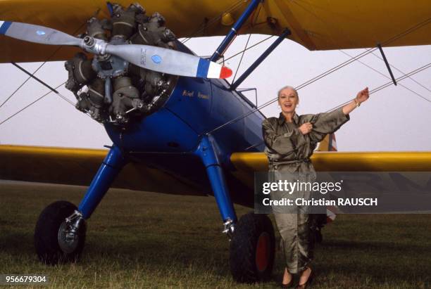 La mannequin française Colette Duval posant en trench-coat d'?Azzedine Alaia?, devant un avion sur une piste de l'aérodrome de la Ferté-Alais, en...