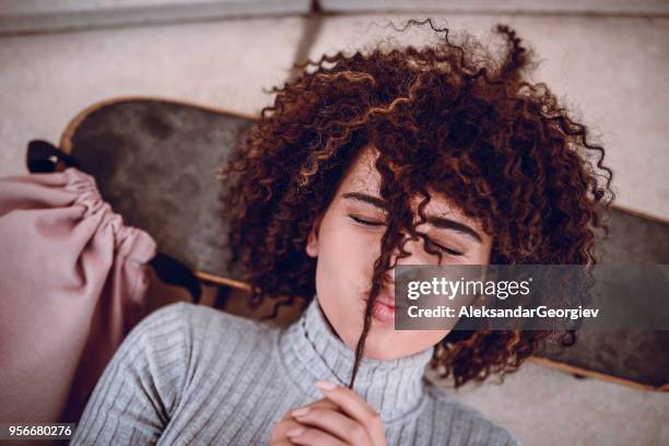 smiling funky girl with curly hair lie on skateboard and blowing kisses - child pulling hair stock pictures, royalty-free photos & images