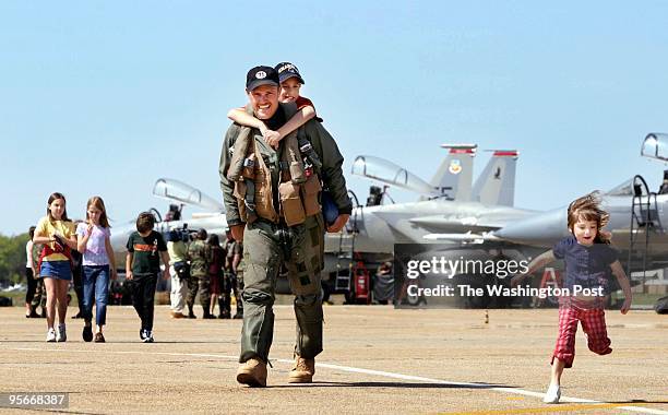 Here with his son Nicholas on his back, Lt. Col. Chris Nowland walks across the tarmac as his daughter Isabella races along beside. Twelve pilots and...