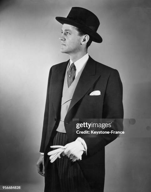 Lawrence Tibbett Jr présentant un modèle de la Custom Tailors and Designers of Amercia : un costume composé d'une redingote bleue, d'un pantalon bleu...