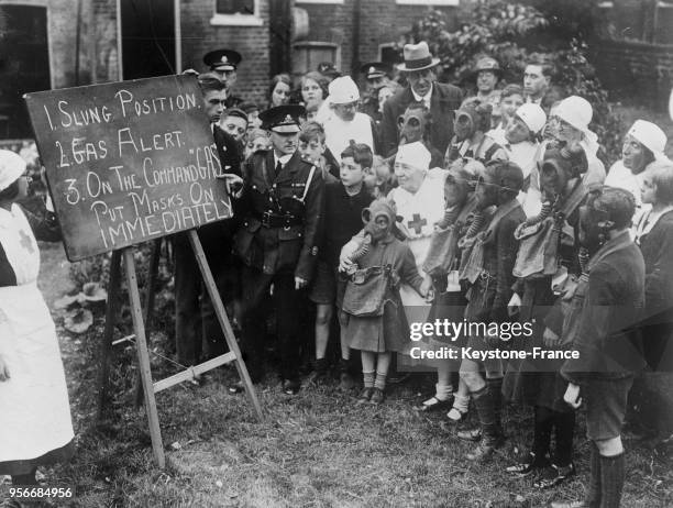 Le commandant Skinner lit devant les élèves d'une école anglaise les indications inscrites sur le tableau noir concernant l'utilisation d'un masque à...