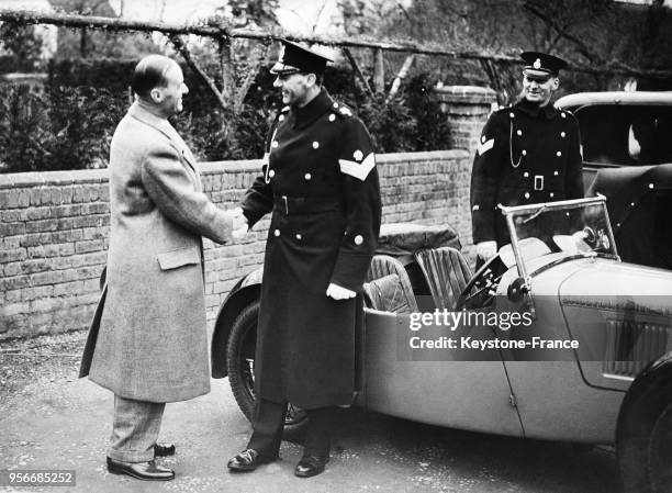 Sir Maclom Campbell, arrivé devant sa maison, serre la main d'un sergent de la Police mobile dont il est le chef, au Royaume-Uni le 6 avril 1935.