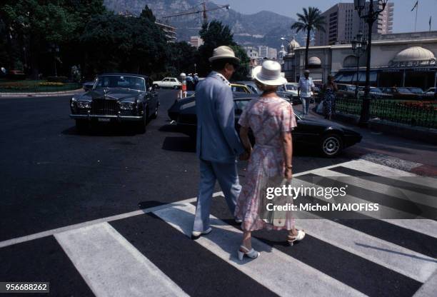 Couple de personnes âgées traversant la rue près d'une voiture de luxe en août 1979 à Monaco.