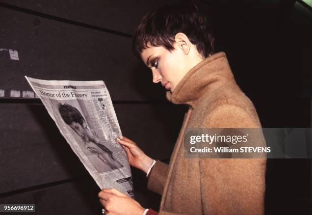 Le mannequin Sibyl Buck lit le journal dans les coulisses d'un défilé Prêt-à- Porter Printemps-Eté 96/97, octobre 1996, Paris, France.