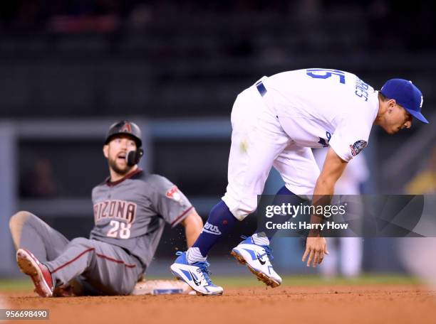 Austin Barnes of the Los Angeles Dodgers loses his balance as Steven Souza Jr. #28 of the Arizona Diamondbacks slides into a force out at second base...