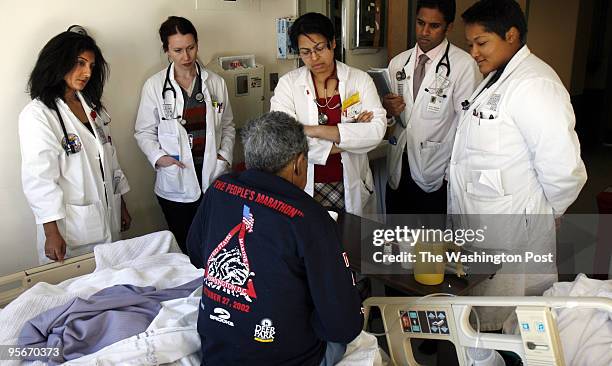 Doctors discuss treatment with a patient whose records they accessed from a laptop computer in the hallway during morning rounds. Pictured are: VA...