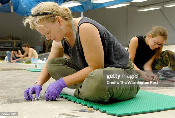 Conservator Mary Wootton uses surgical gloves and a surgical needle to re-enforce the seam. They have added to the top and the bottom of the...