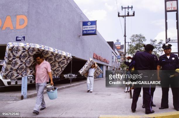 Deux hommes marchant avec un matelas sur les épaules après le tremblement de terre meurtrier en septembre 1985 à Mexico, Mexique.