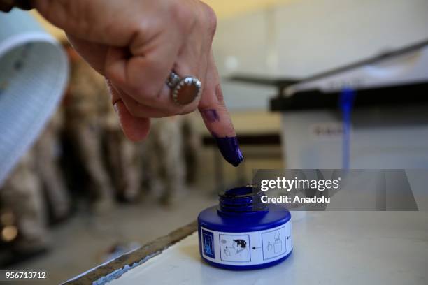 Iraqi security forces takes his finger out from a ink bottle after casting his vote during the special voting day for the Iraqi parliamentary...