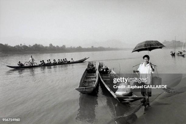 Une laotienne à l'embarcadère, en avril 1995 non loin de Luang Prabang, Laos. Un autre bateau fait traverser la rivière à ses passagers.