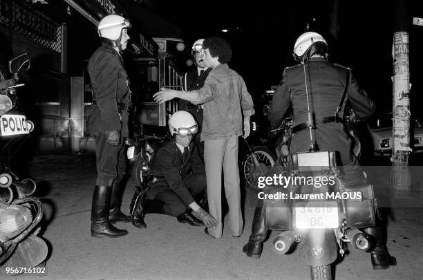 Un jeune homme subit un contrôle et une fouille au corps par des motards de la Police nationale le 5 juin 1983 à Paris, France.