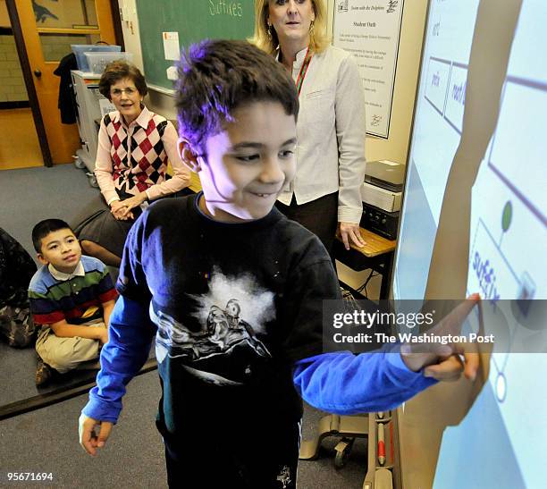 At Sleepy Hollow Elementary School, Jason Portales uses his finger to drag the correct answer into position on the interactive white board. Behing...