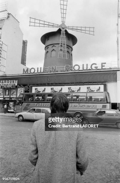 Un touriste devant le Moulin Rouge à Paris en juin 1981, France.