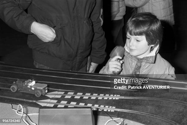 Un enfant joue avec un circuit de voitures au salon du jouet et du modèle réduit au CNIT à La Défense à Paris le 2 avril 1983, France.