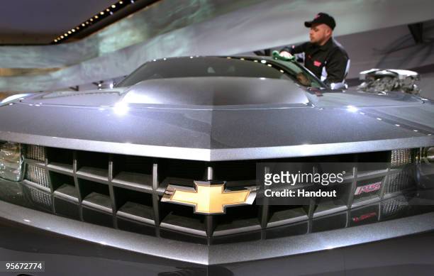 In this handout image provided by General Motors, Mike Duncan cleans a 2010 Chevrolet Camaro RS in the General Motors exhibit of the North American...