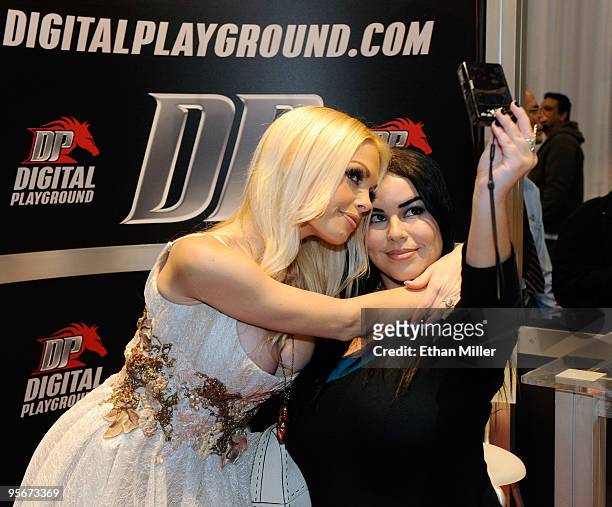 Adult film actress Jesse Jane takes a photo with attendee A. Valentin of California at the Digital Playground booth at the 2010 AVN Adult...
