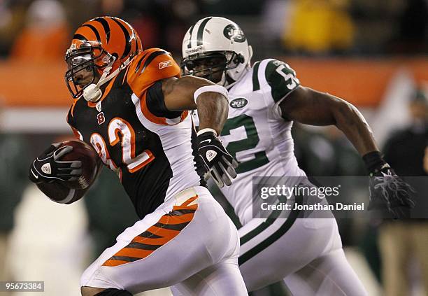 Cedric Benson of the Cincinnati Bengals runs the ball alongside David Harris of the New York Jets in the third quarter during the 2010 AFC wild-card...